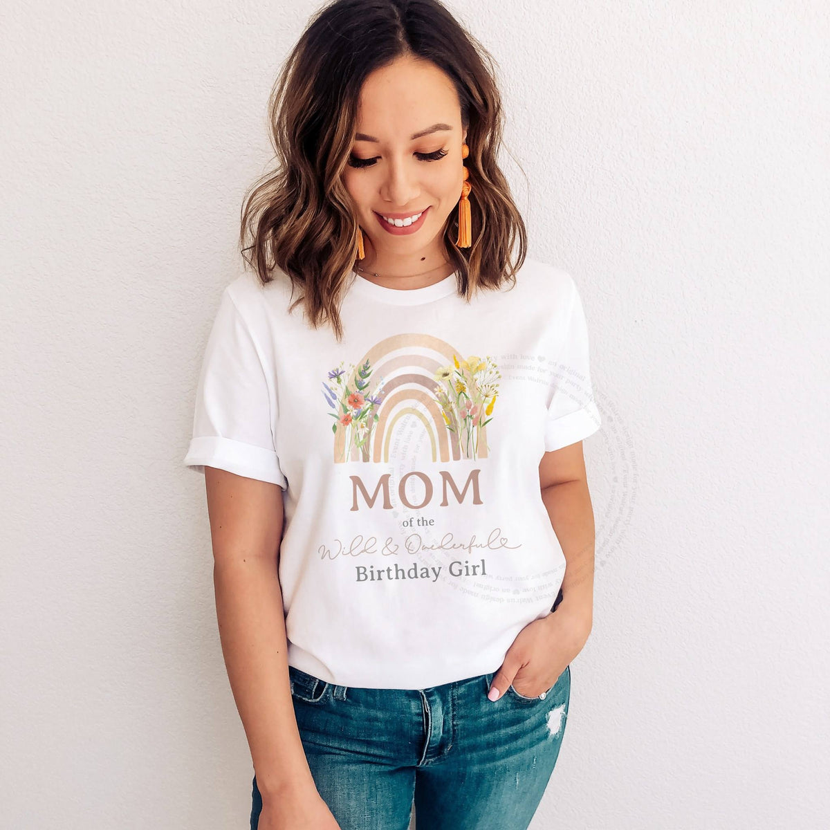 Woman in a white Mom of the Wild and Onederful Birthday Girl tee with a pastel rainbow.