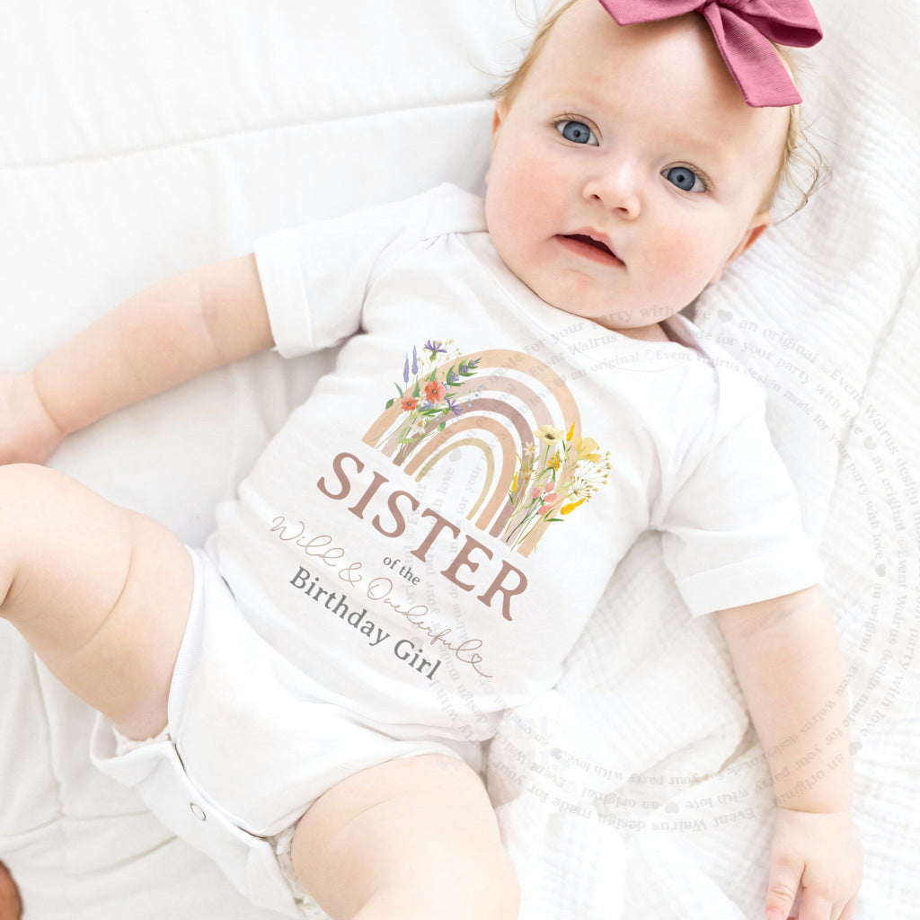 Baby girl with a pink bow in a white Sister of the Wild and Onederful Birthday Girl bodysuit.