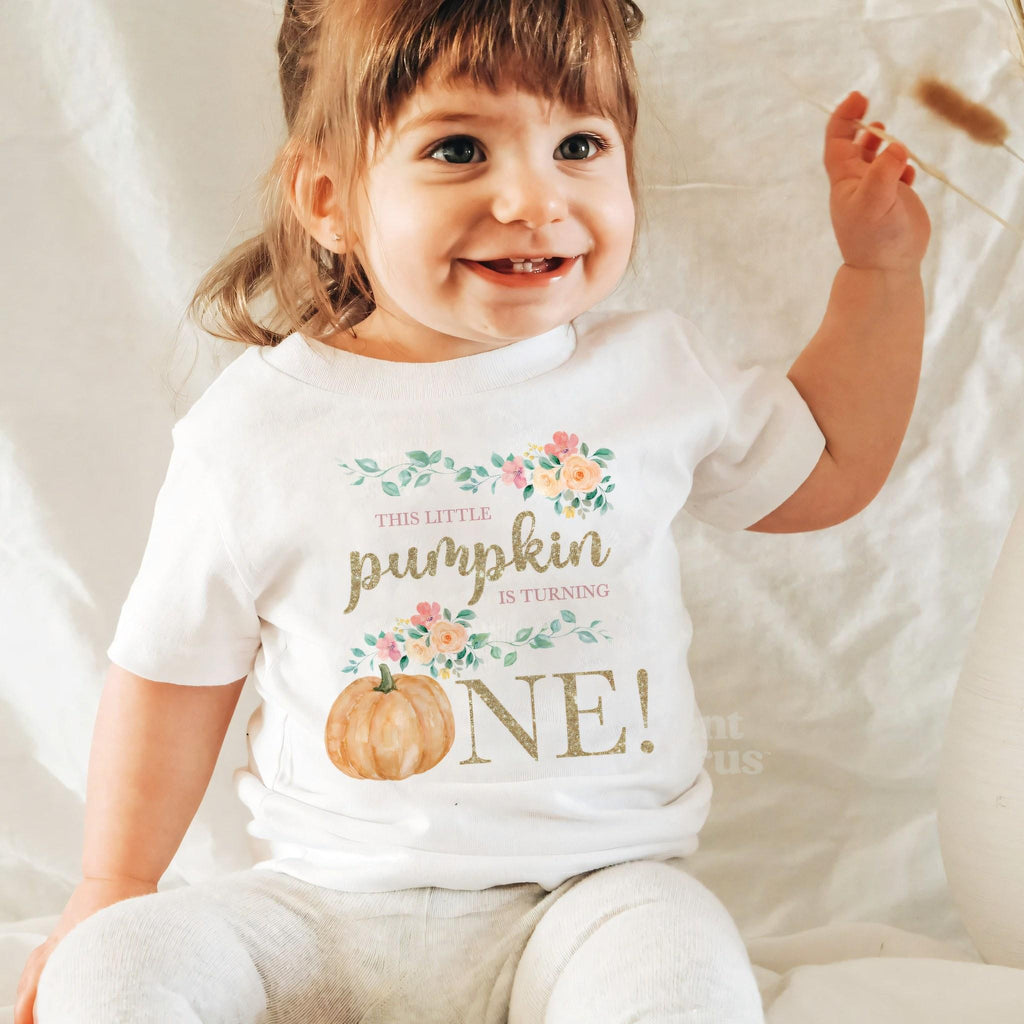 Laughing baby girl in a white floral Little Pumpkin baby tee.