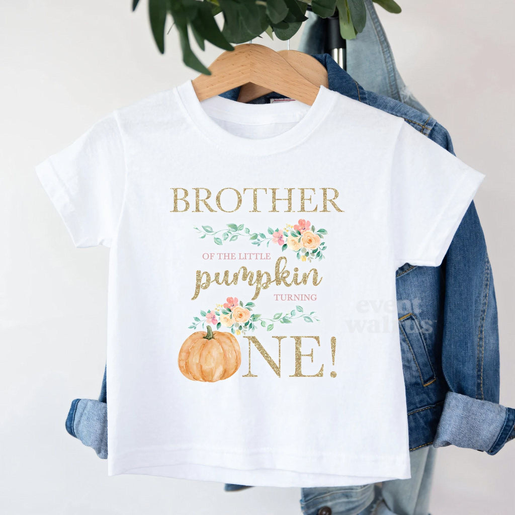 White Brother of the Little Pumpkin toddler tee on a hanger over a denim jacket.
