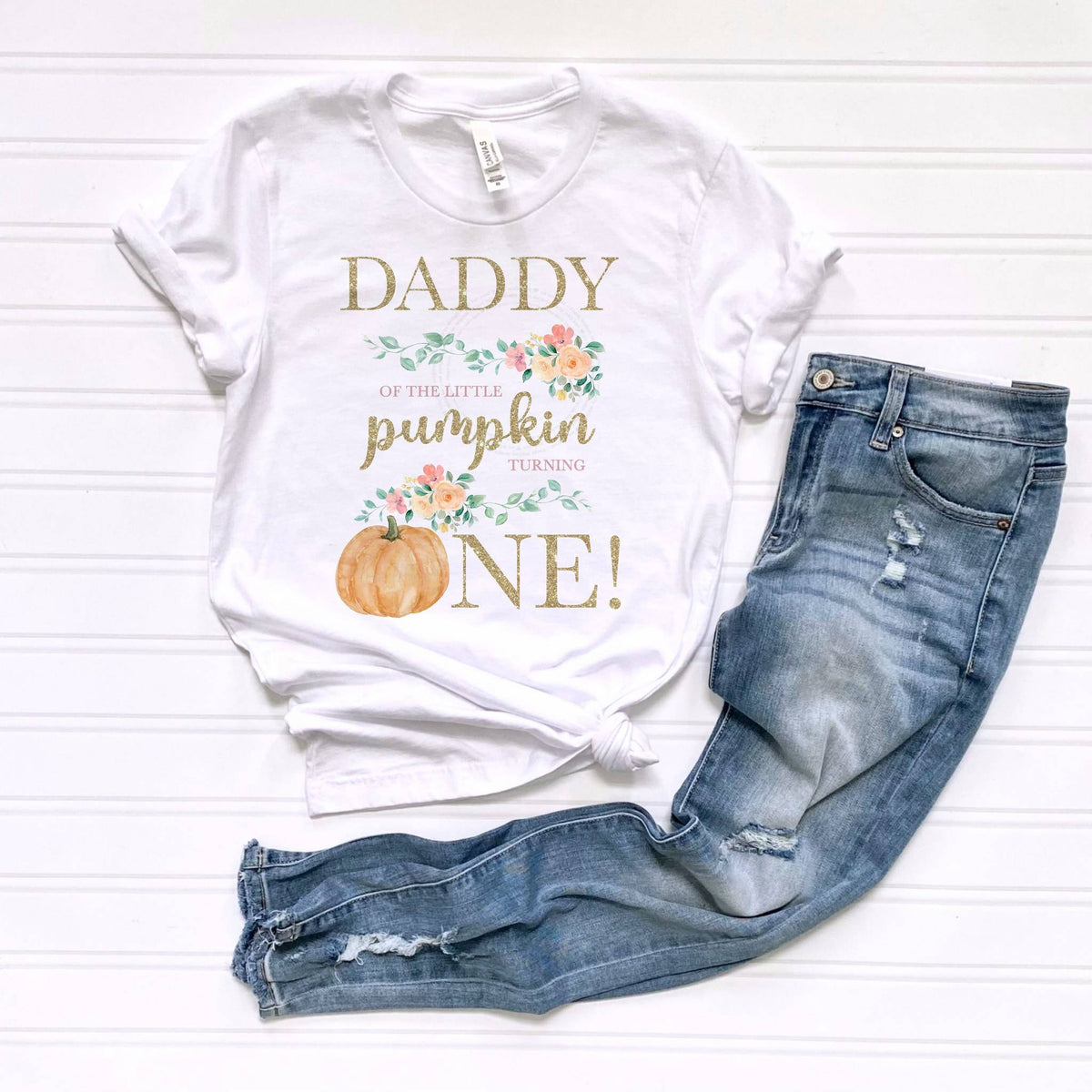 White Daddy of the Little Pumpkin tee laid flat beside jeans.