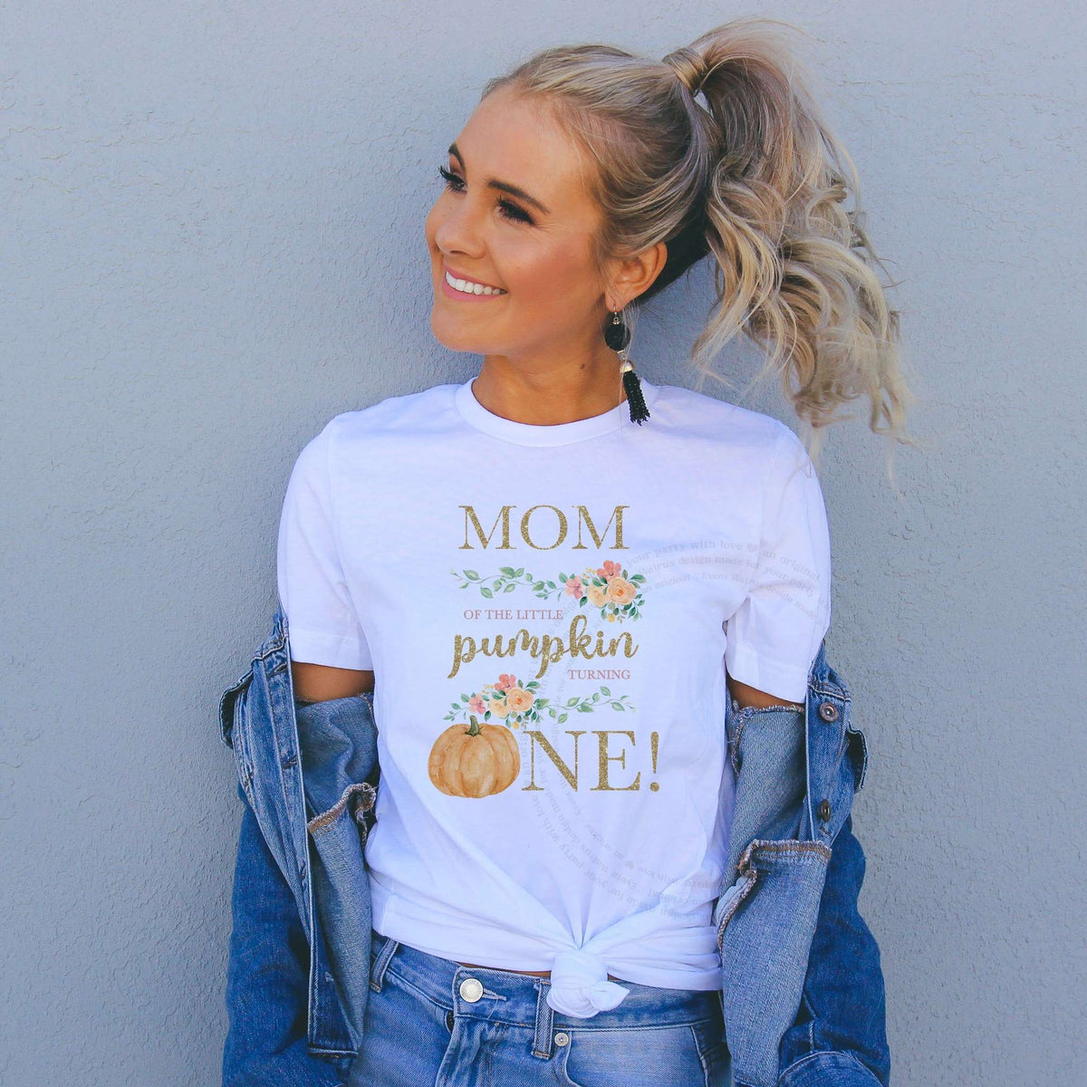 Woman in a denim jacket wearing a Mom of the Little Pumpkin shirt with a peach pumpkin.