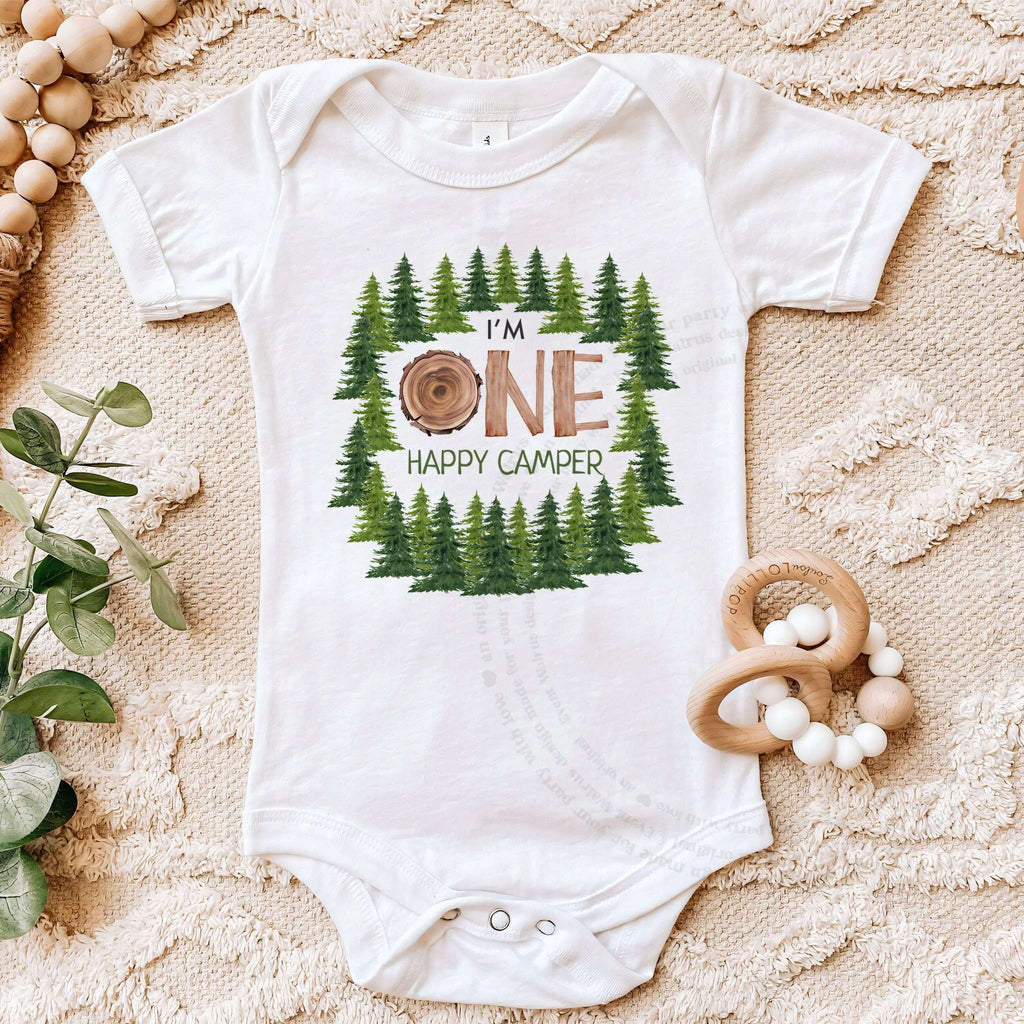 White I'm One Happy Camper bodysuit on a beige blanket with a wooden teether.