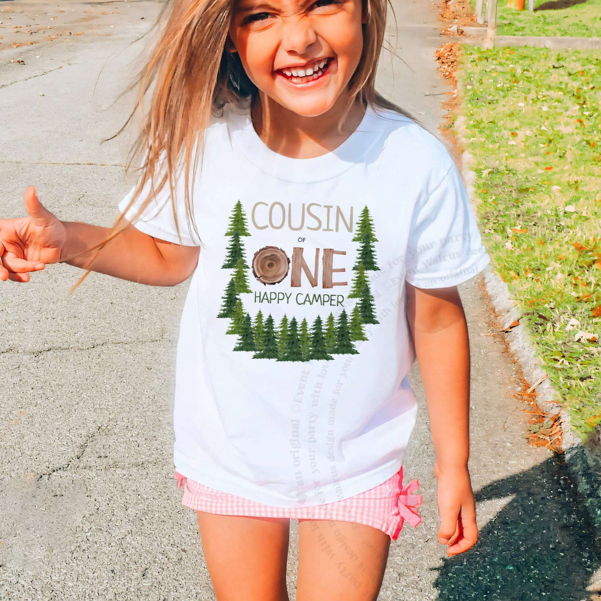 Laughing girl outdoors in a white Cousin One Happy Camper kids tee.