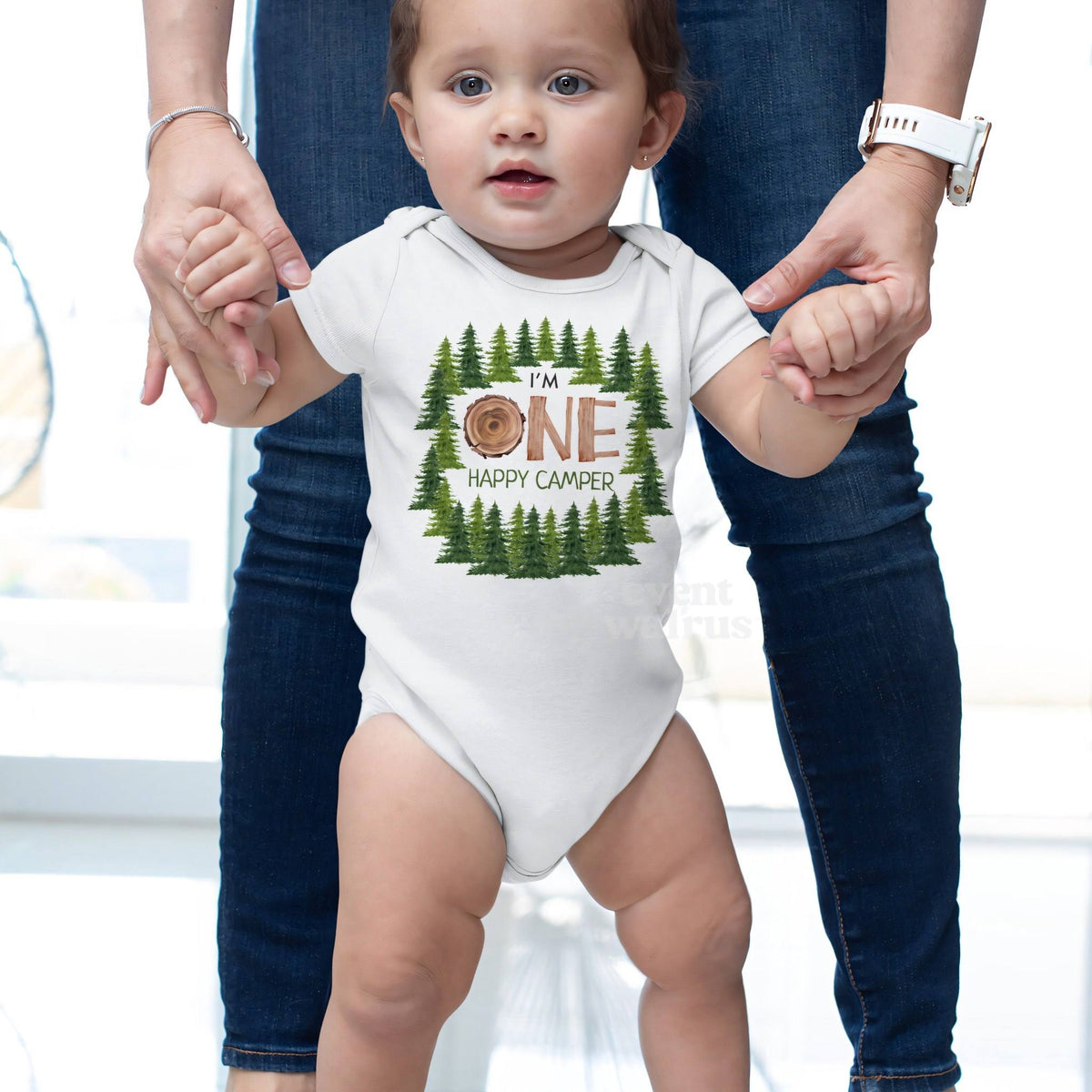 Baby taking steps while holding Mom's hands, in a white I'm One Happy Camper bodysuit.