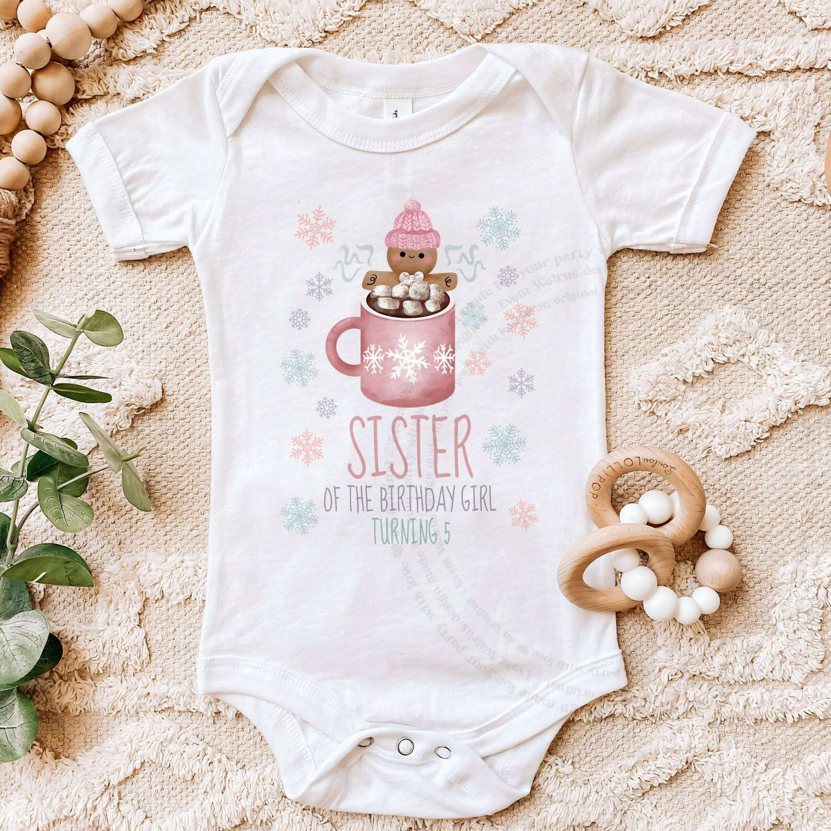 White pink Cookies and Cocoa Sister bodysuit on a beige blanket with a wooden teether.