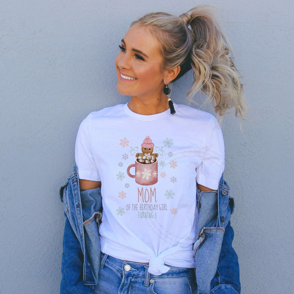 Woman in a denim jacket wearing a Mom of the Birthday Girl Turning 5 shirt with a cocoa mug.