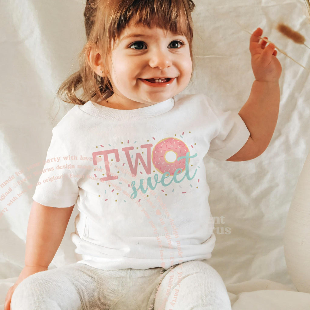 Laughing little girl in a white Two Sweet birthday tee with a pink donut.