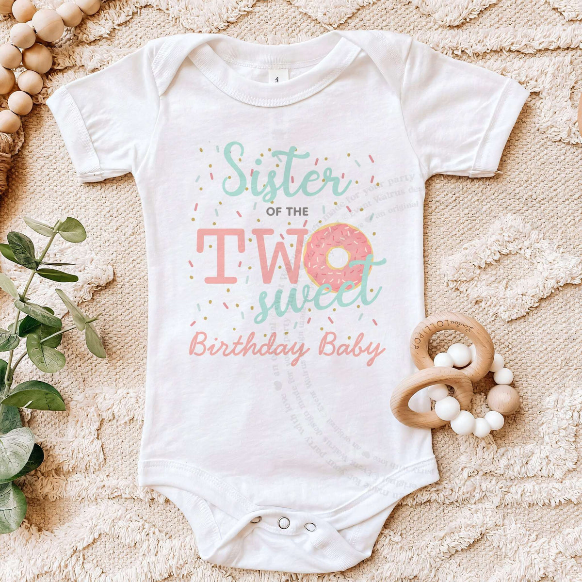 White Sister of the Two Sweet bodysuit on a beige blanket with a wooden teether.