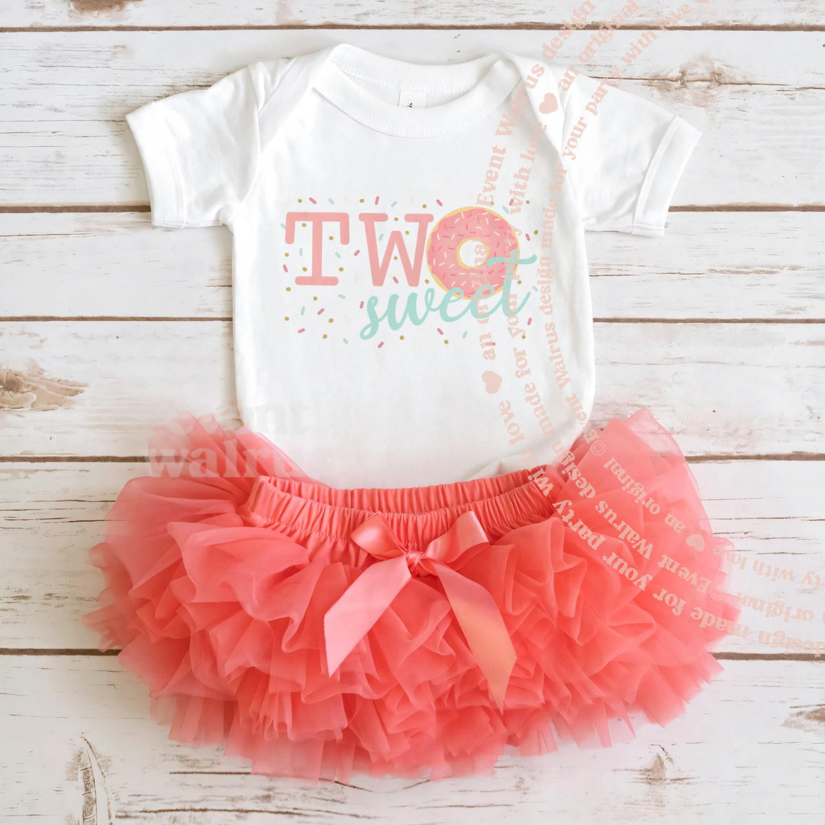 White Two Sweet donut bodysuit laid flat with a coral tutu on whitewashed wood.