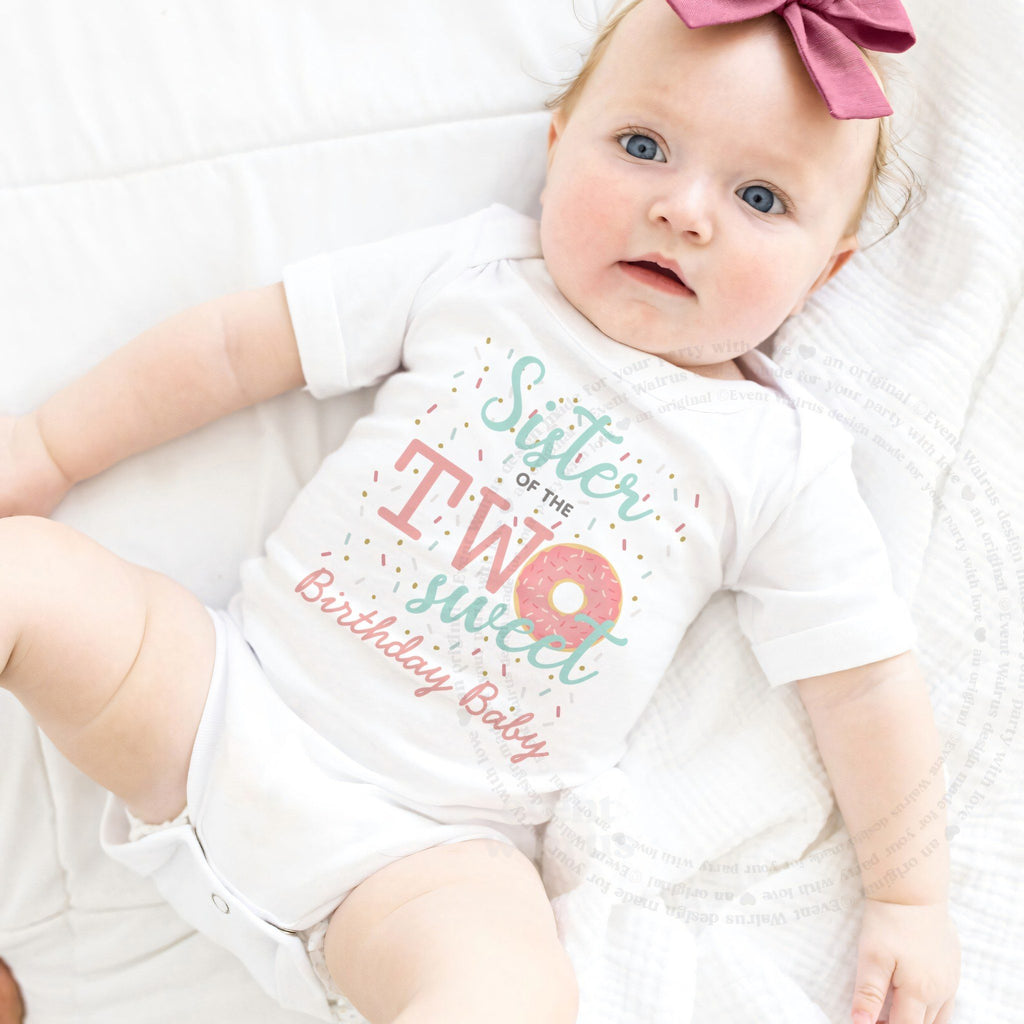 Baby girl with a pink bow lying in a white Sister of the Two Sweet bodysuit.