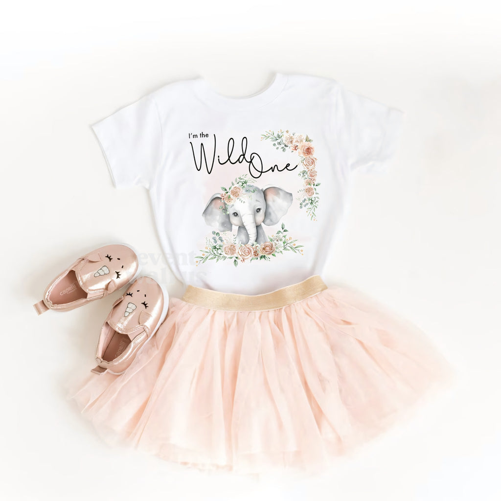 White I'm the Wild One toddler tee laid out with a blush tutu and pink baby shoes.
