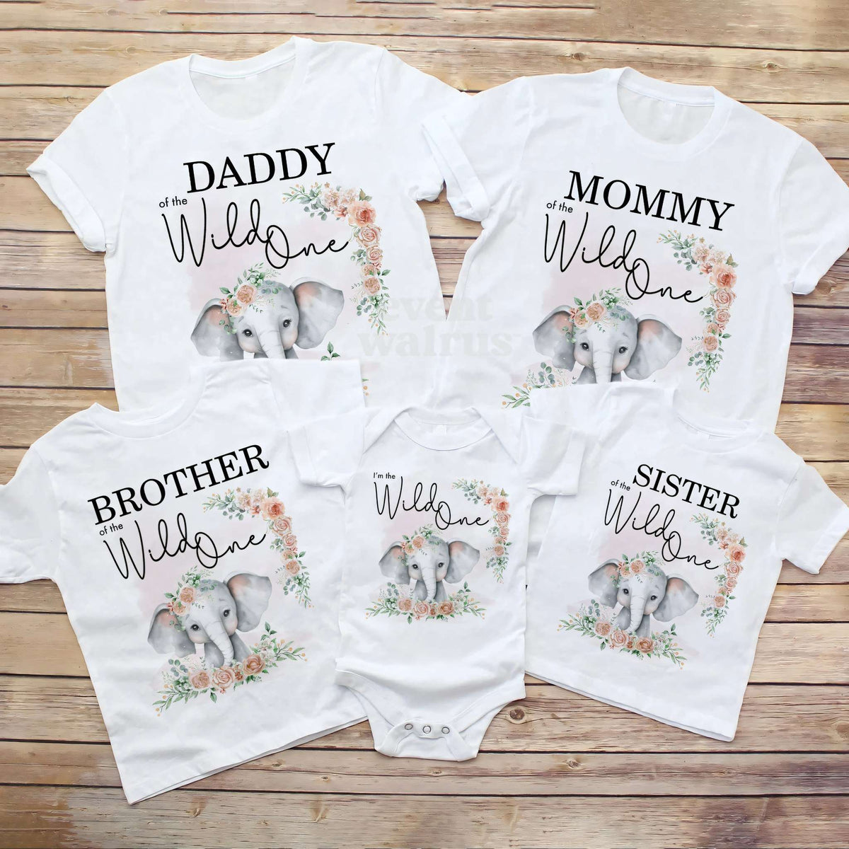 Daddy, Mommy, Brother, Sister and baby elephant Wild One shirts laid out on a wood table.