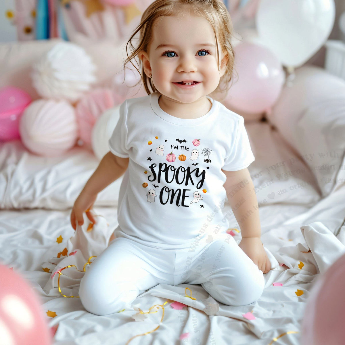Smiling toddler girl among pink balloons in a white I'm the Spooky One tee.