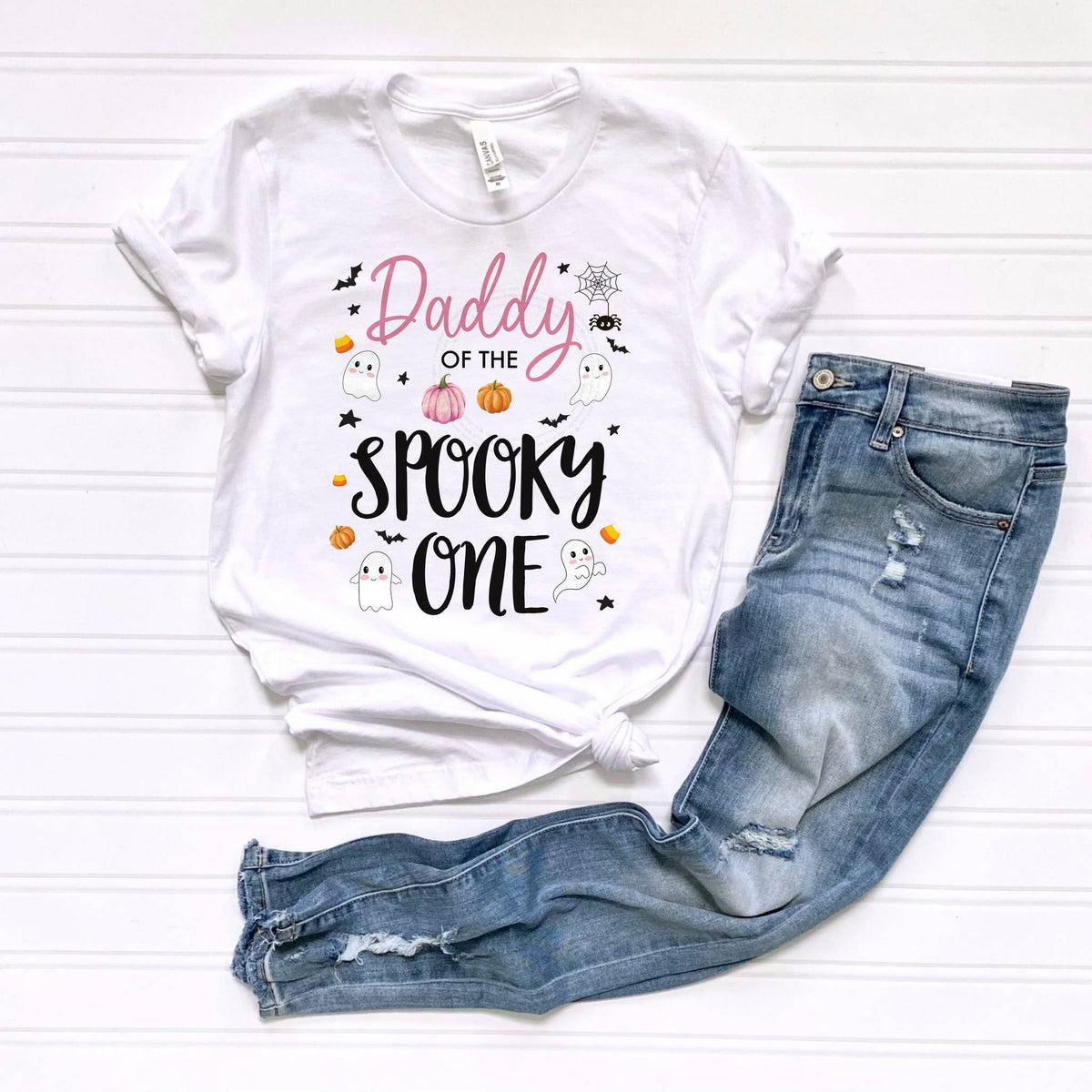 White Daddy of the Spooky One tee laid flat beside jeans.