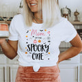Woman holding a mug in a white Mom of the Spooky One shirt.
