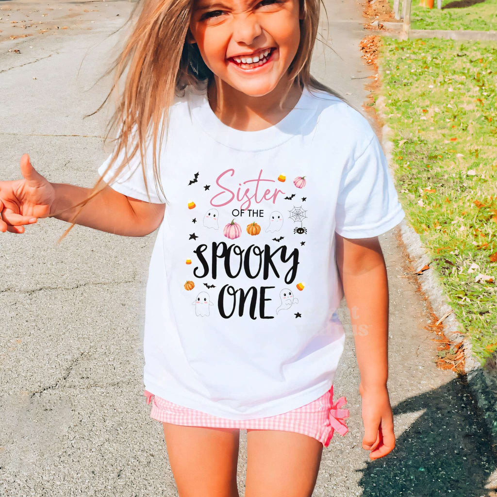 Laughing girl outdoors in a white Sister of the Spooky One kids tee.