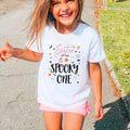 Laughing girl outdoors in a white Sister of the Spooky One kids tee.