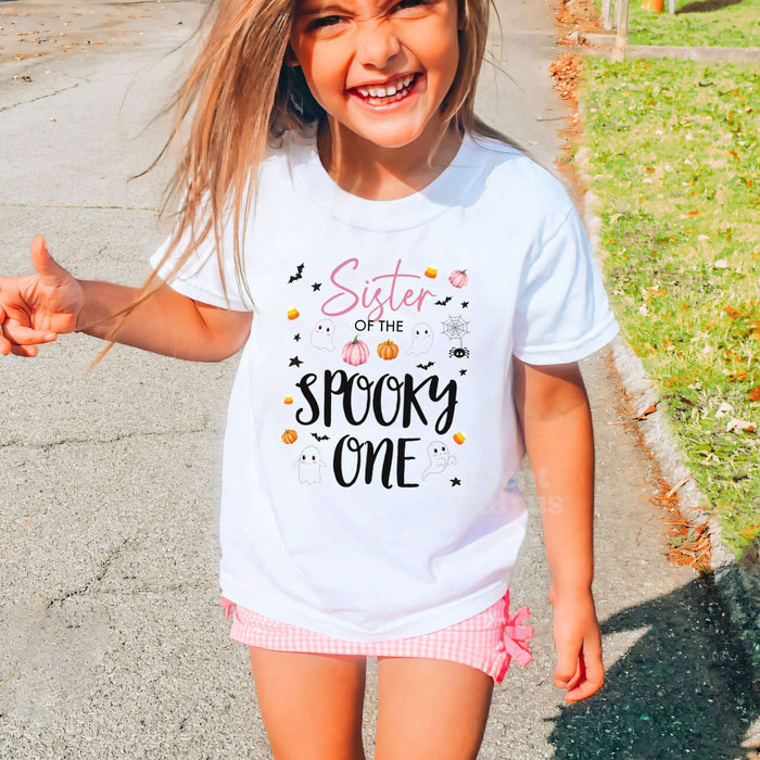 Laughing girl outdoors in a white Sister of the Spooky One kids tee.