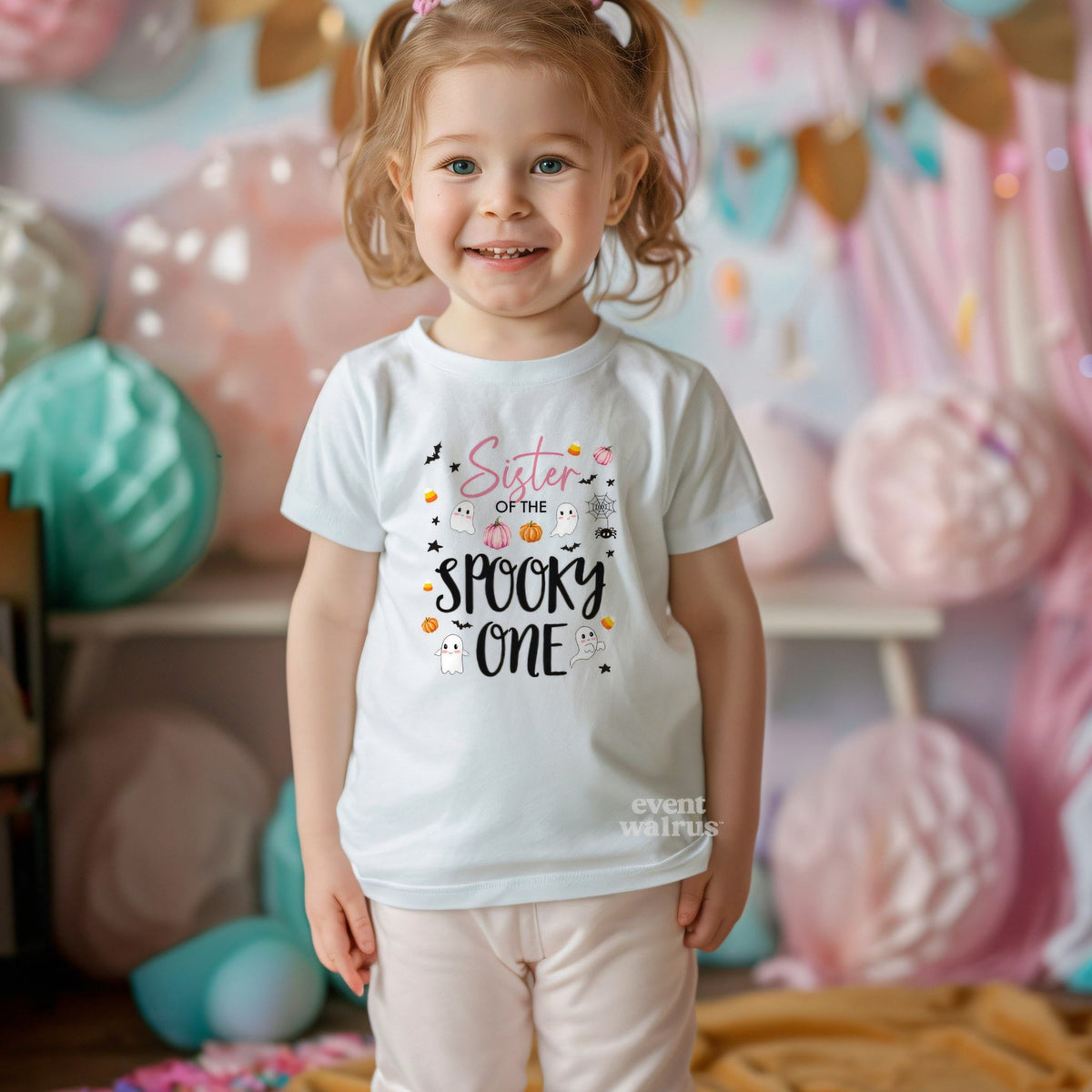 Toddler girl with pigtails in a white Sister of the Spooky One tee at a pastel party.