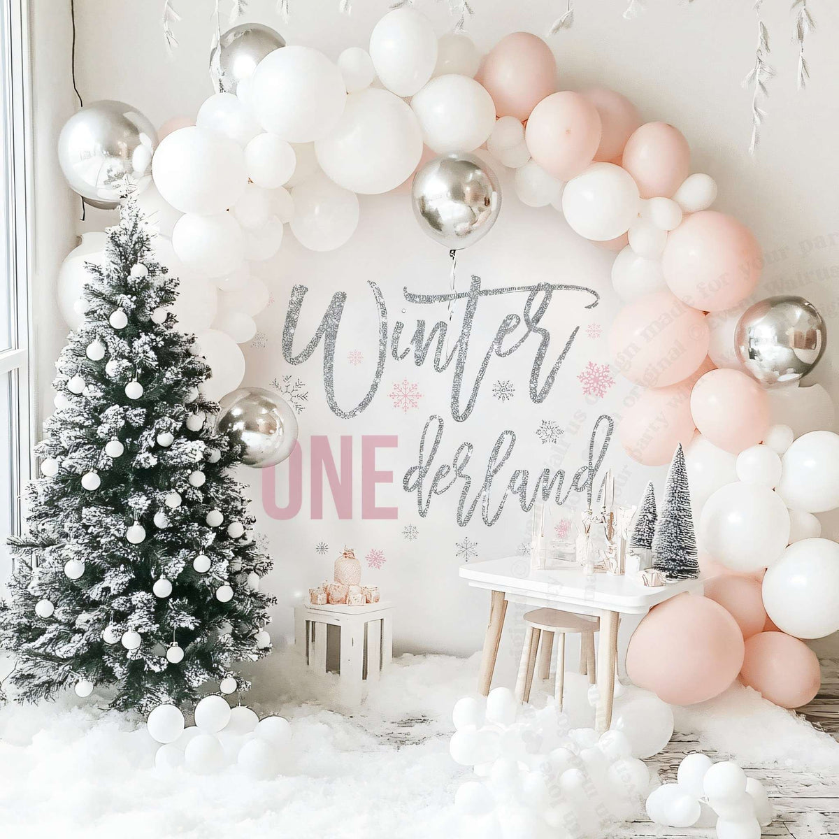 Pink winter onederland backdrop beside a flocked Christmas tree under a blush and white balloon arch.