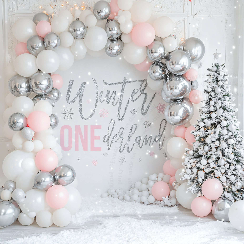 Winter onederland first birthday backdrop framed by a silver, white and pink balloon arch.