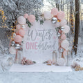 Pink glitter winter onederland backdrop in snowy woods with pink and silver balloons and lanterns.