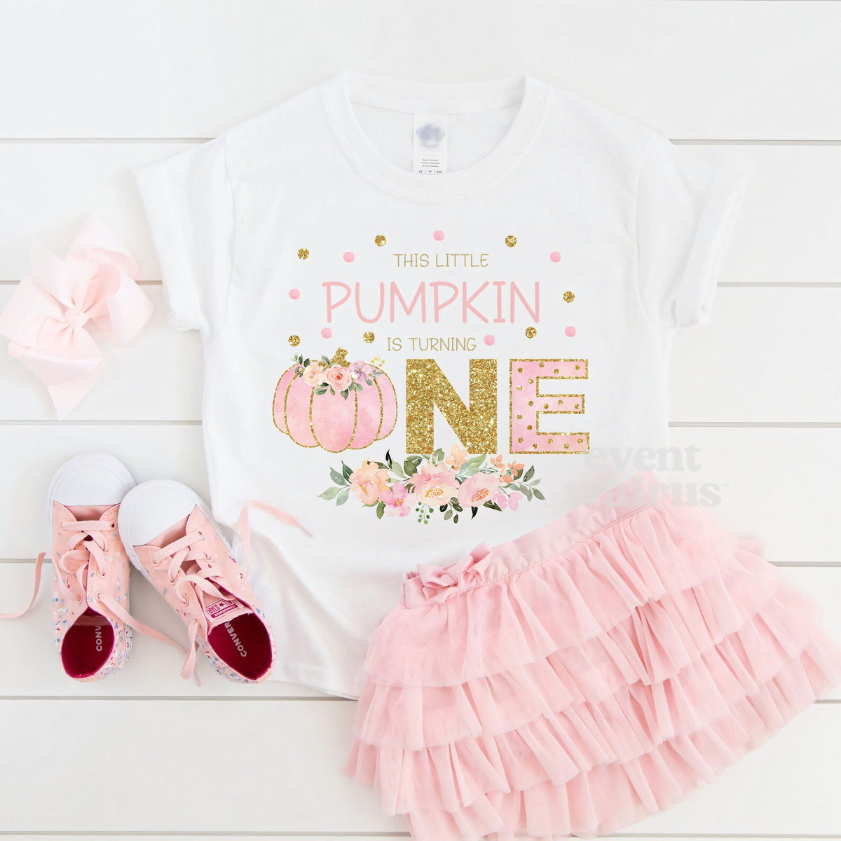 White This Little Pumpkin Is Turning One toddler tee laid flat with a pink tutu and sneakers.