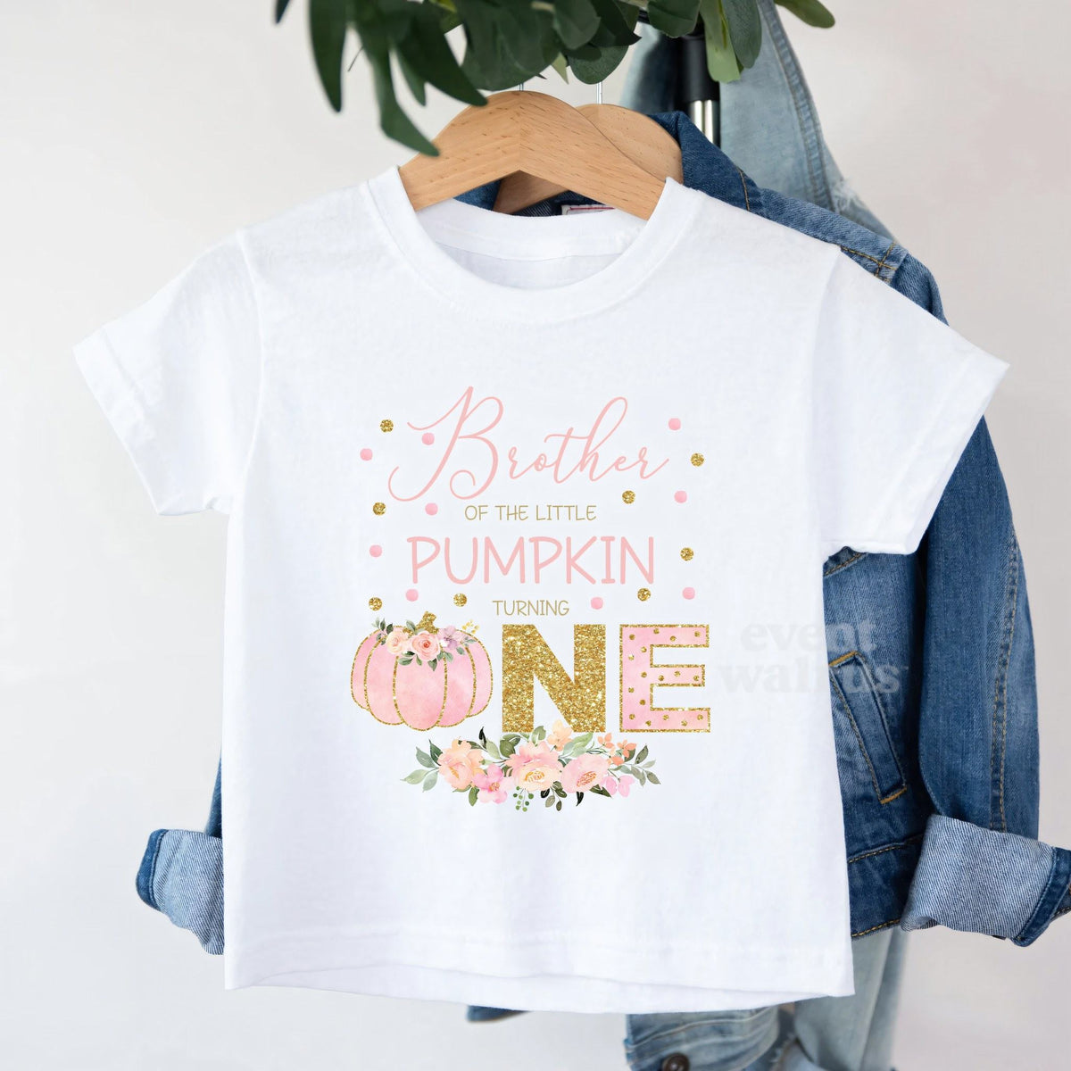 White Brother of the Little Pumpkin toddler tee on a hanger over a denim jacket.