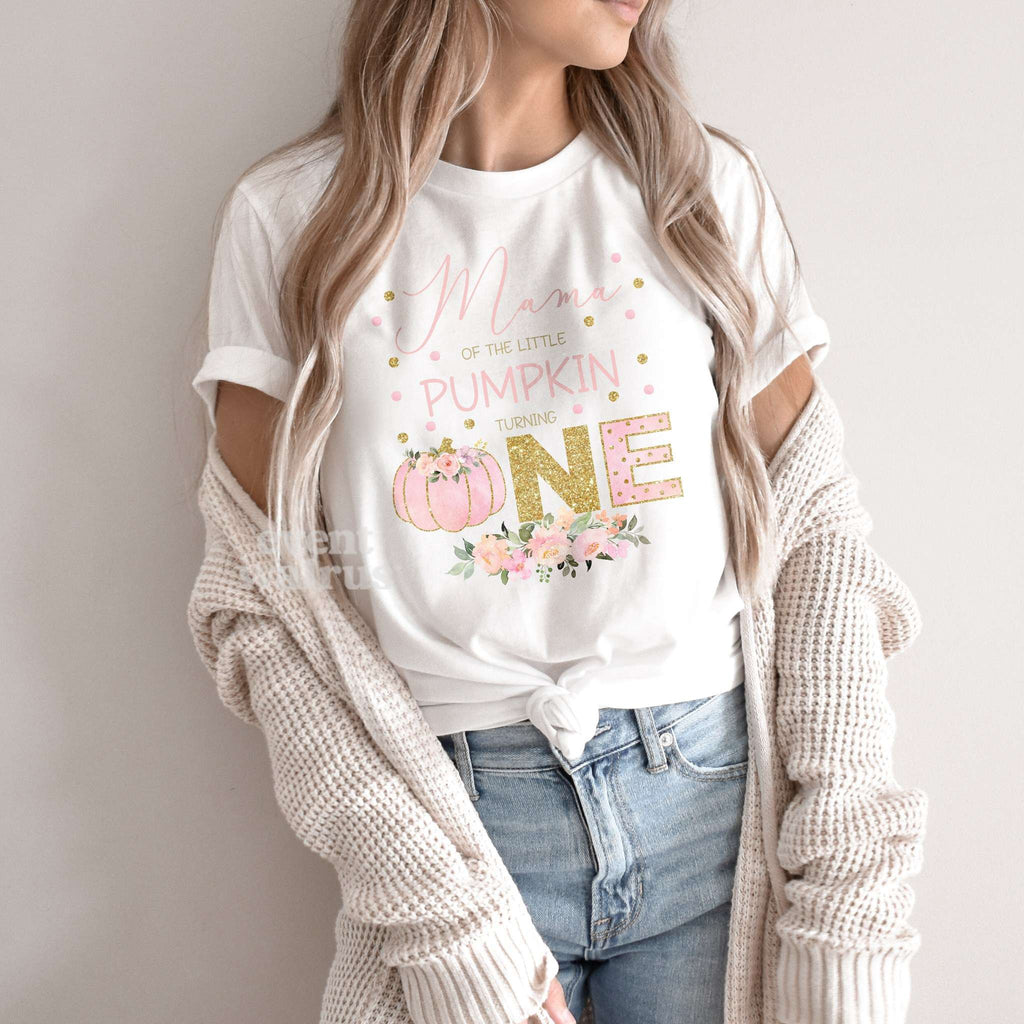 Woman in a knit cardigan wearing a white pink and gold Little Pumpkin Turning One shirt.