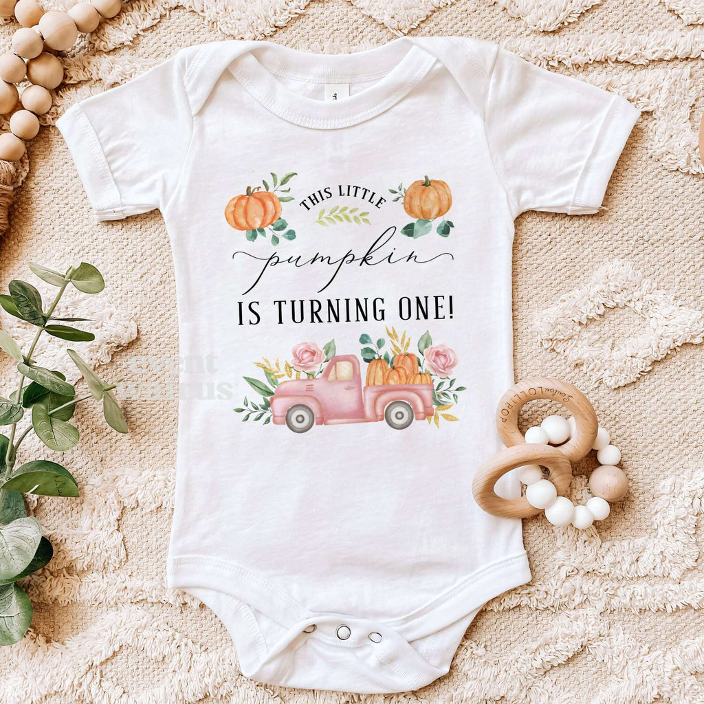 White Little Pumpkin bodysuit on a beige blanket with a wooden teether.