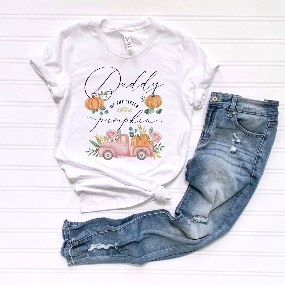 White Daddy of the Little Pumpkin tee laid flat beside jeans.