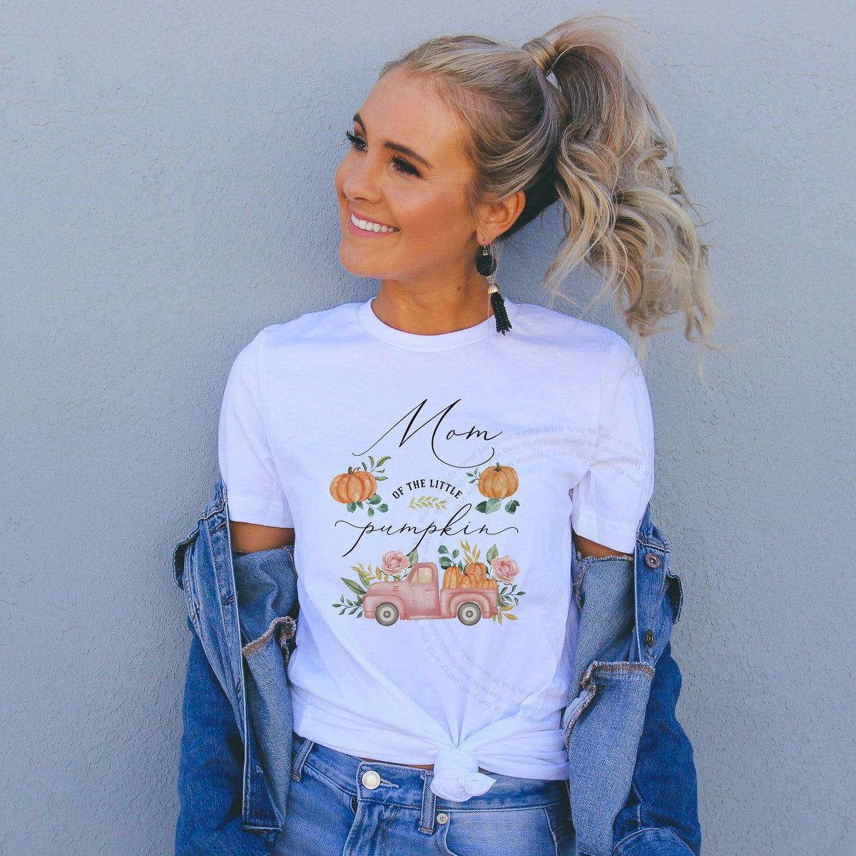 Woman in a denim jacket wearing a Mom of the Little Pumpkin shirt with a pink pickup.