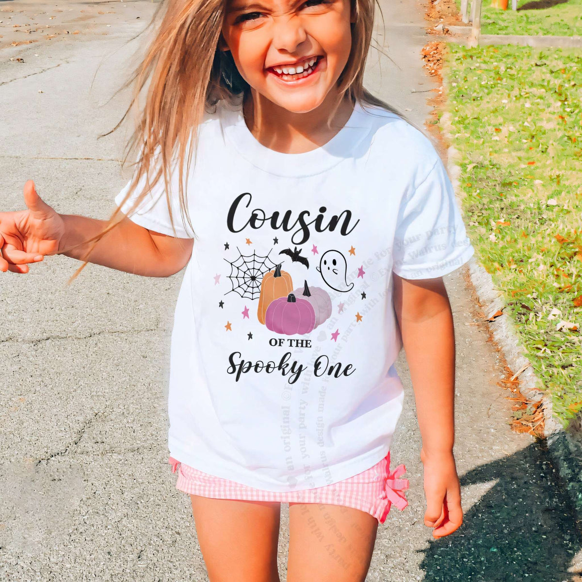 Laughing girl outdoors in a white Cousin of the Spooky One kids tee.