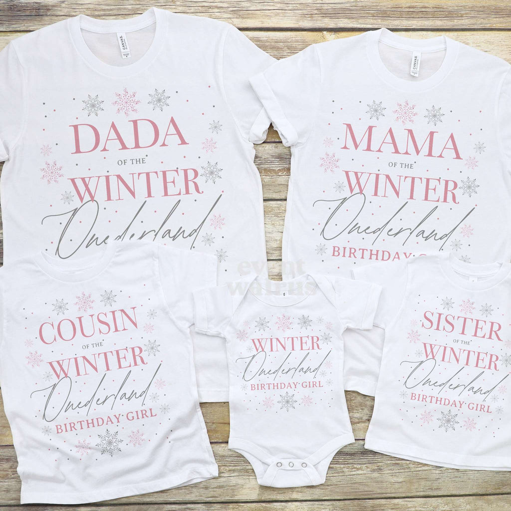 Winter Onederland bodysuit laid out with the Dada, Mama, Cousin and Sister shirts on wood.