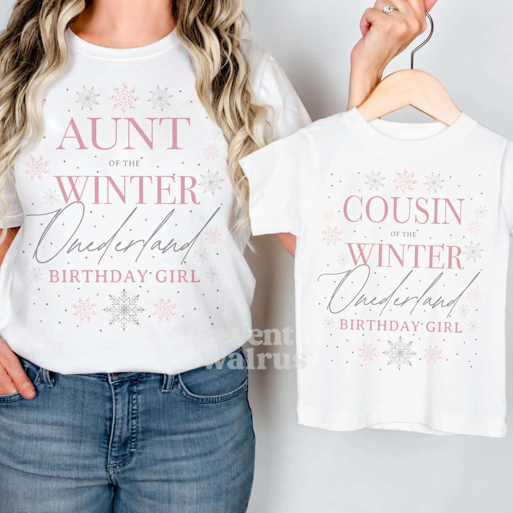 Aunt holding up a white Cousin Winter Onederland kids tee on a hanger while wearing her own.