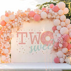 Pink sprinkle donut backdrop framed by a full blush and peach balloon wall.