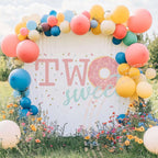 Pink donut two sweet backdrop in a wildflower field with a bright balloon arch.