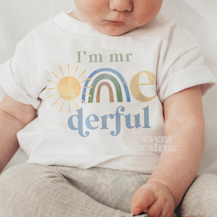 Baby sitting up in a white I'm Mr Onederful baby tee with the pastel rainbow.