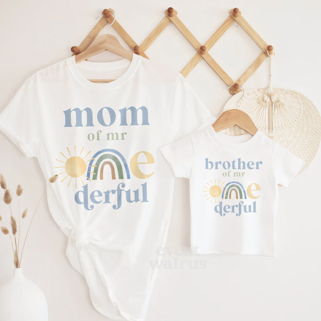White Brother of Mr Onederful tee hanging beside the Mom shirt on a peg rail.