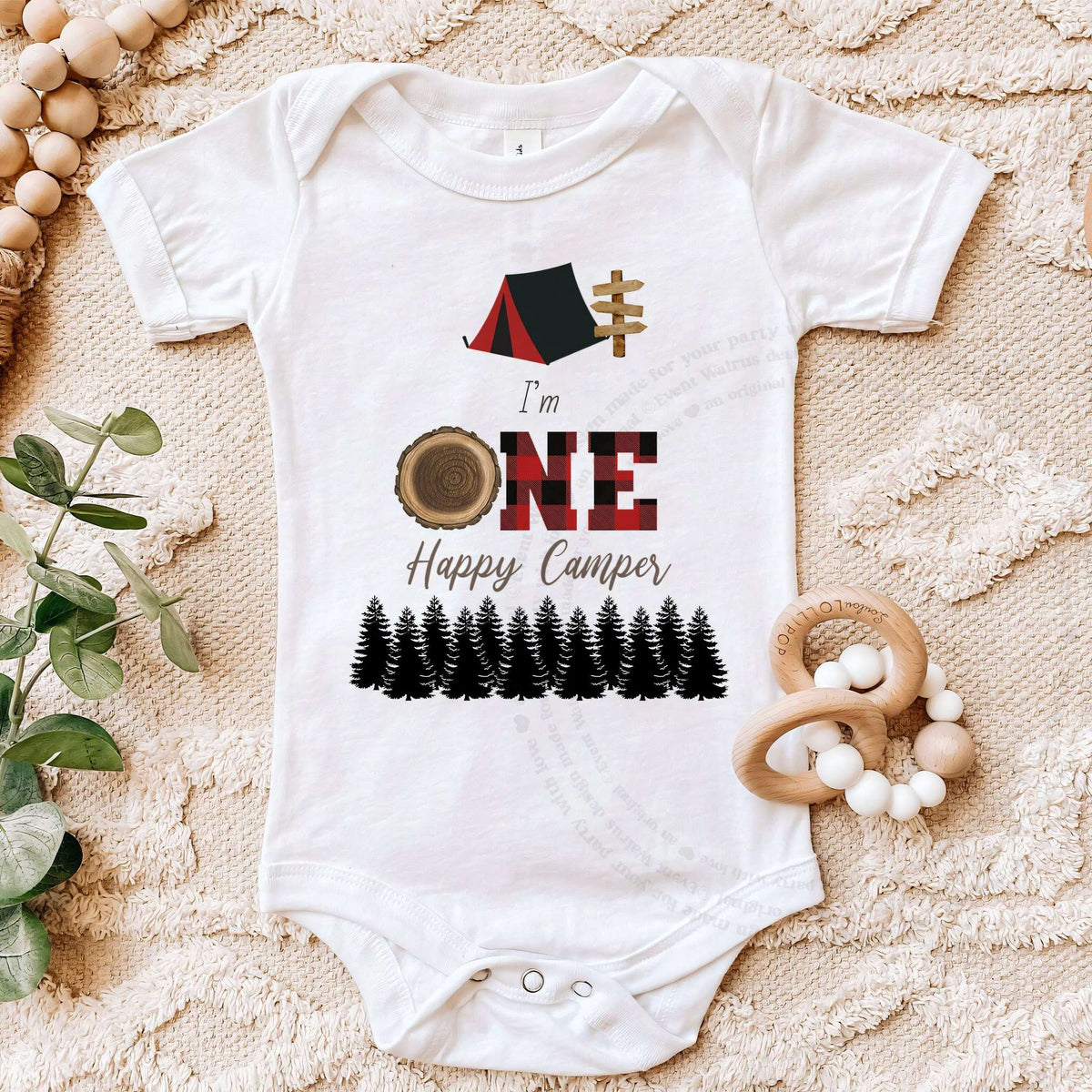 White One Happy Camper bodysuit on a beige blanket with a wooden teether.
