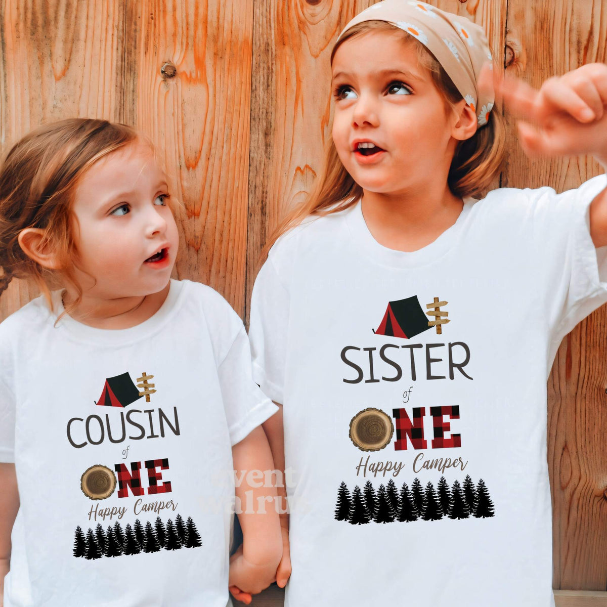 Cousin and sister against a wood wall in white red plaid camper shirts.