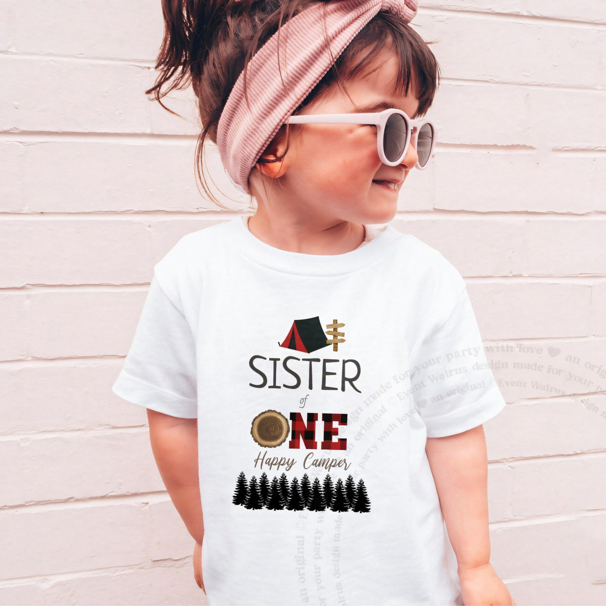 Girl in sunglasses and a pink headband wearing a white Sister of One Happy Camper shirt.
