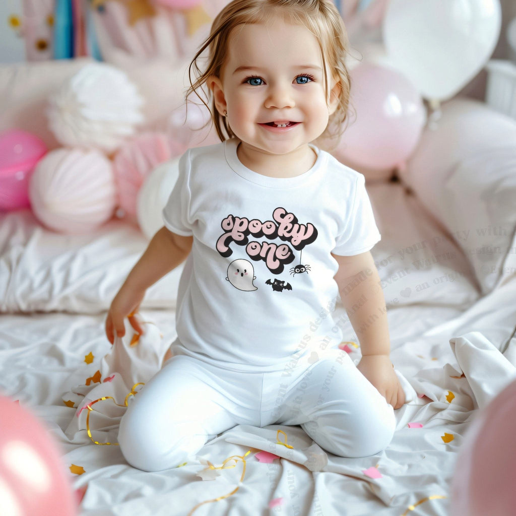 Smiling toddler girl among pink balloons in a white retro pink Spooky One tee.