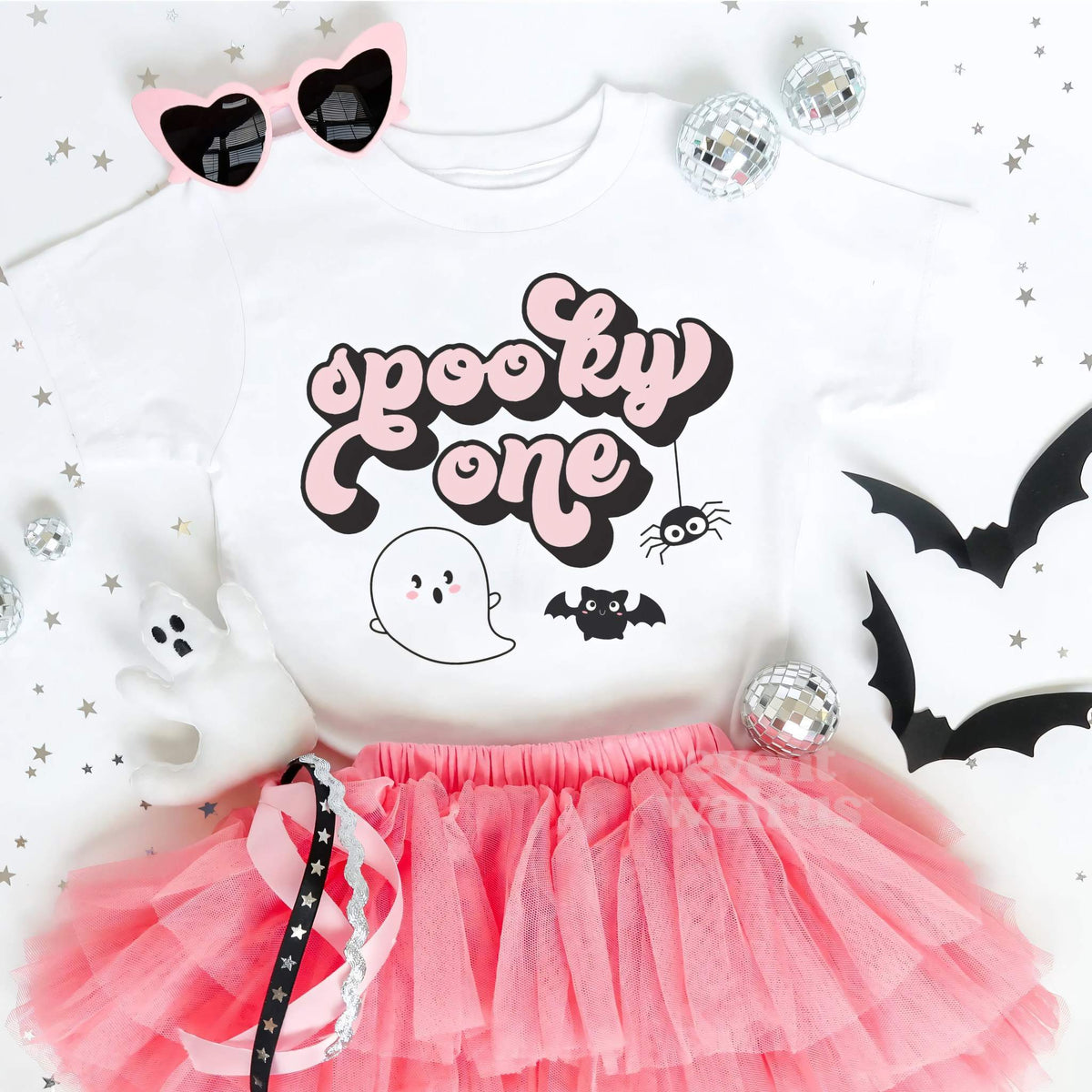 White Spooky One toddler tee laid flat with a pink tutu, heart sunglasses and paper bats.