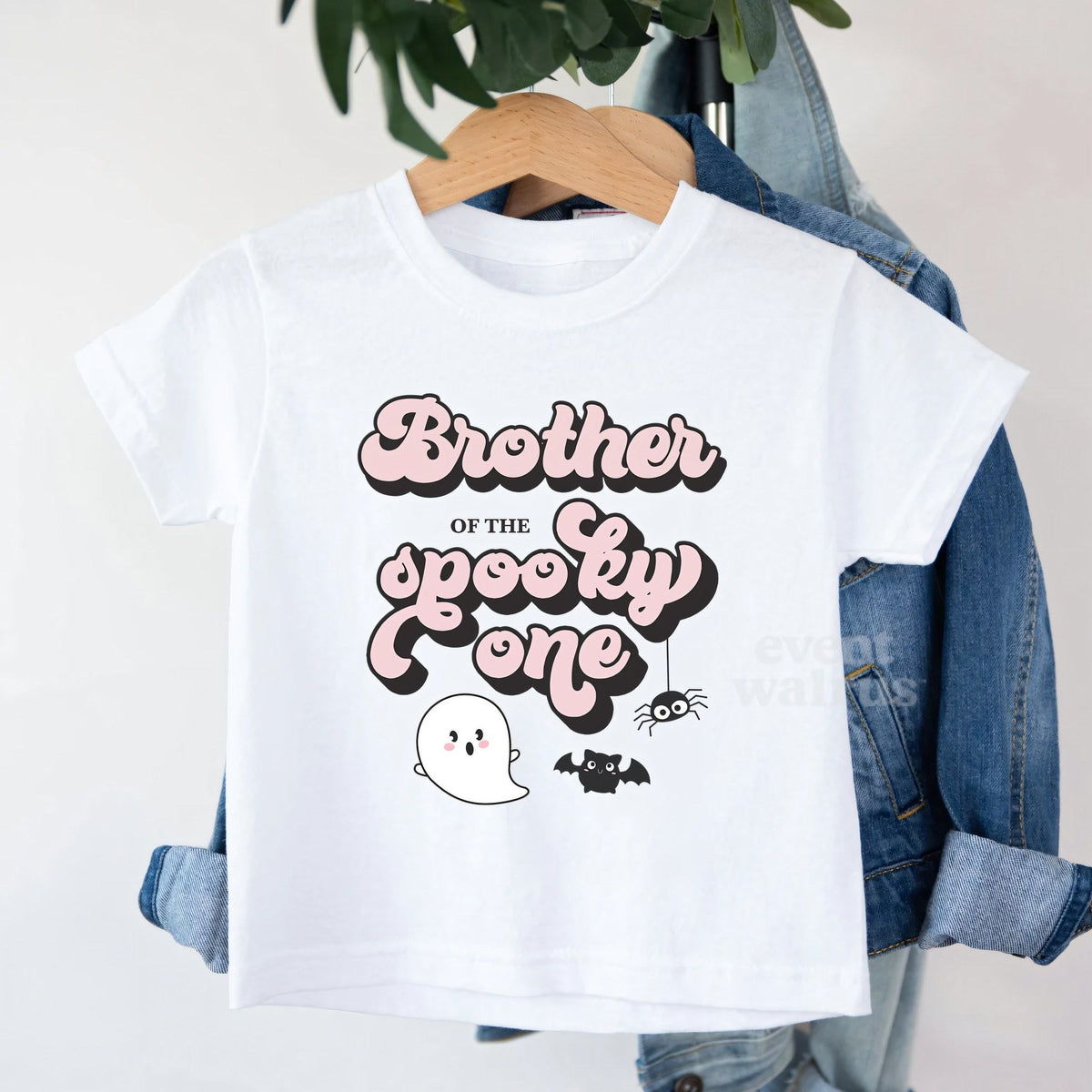 White Brother of the Spooky One toddler tee on a hanger over a denim jacket.