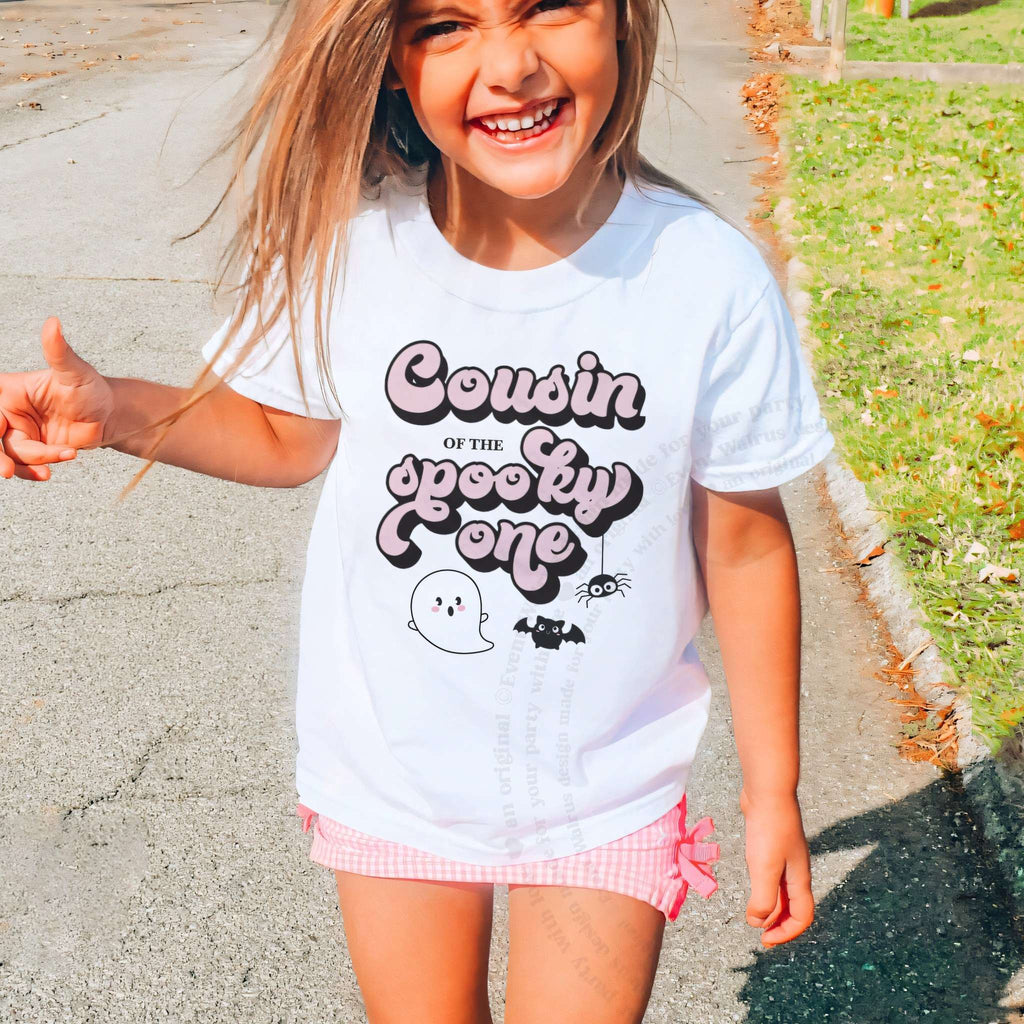 Laughing girl outdoors in a white Cousin of the Spooky One kids tee.