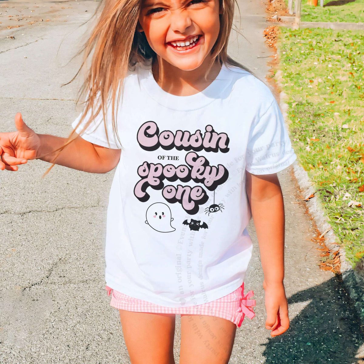 Laughing girl outdoors in a white Cousin of the Spooky One kids tee.