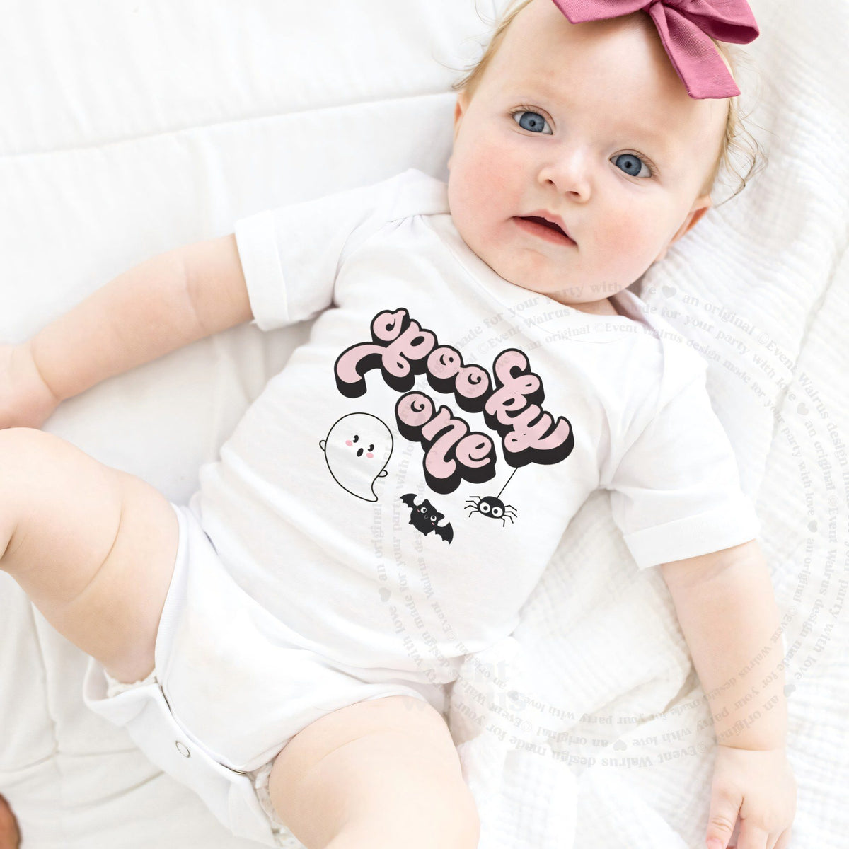 Baby girl with a pink bow lying in a white retro pink Spooky One bodysuit.