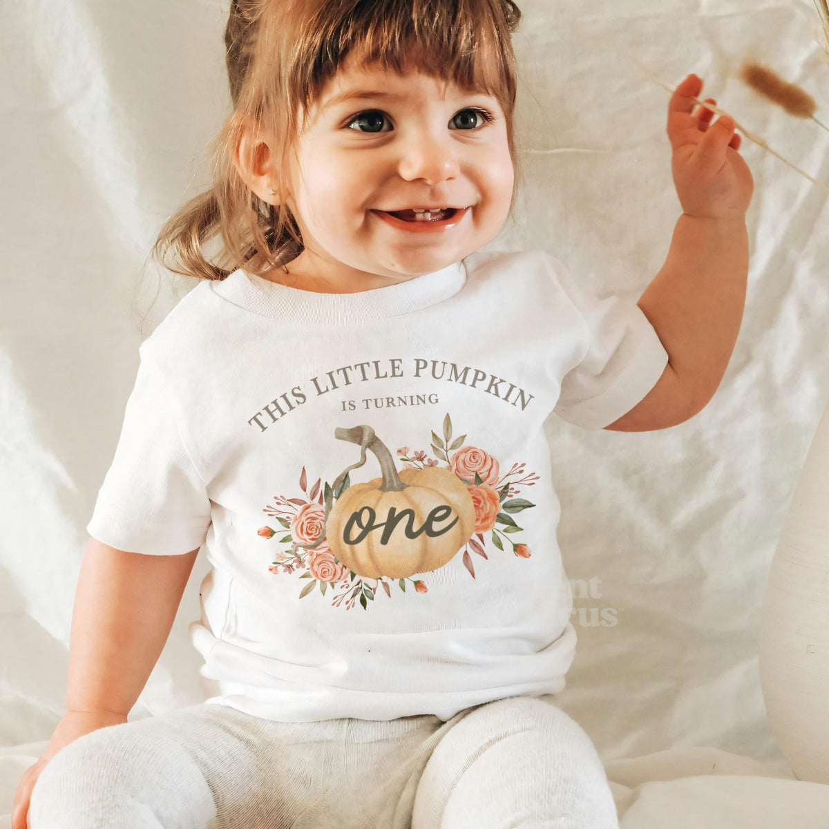 Laughing baby girl in a white Little Pumpkin baby tee.